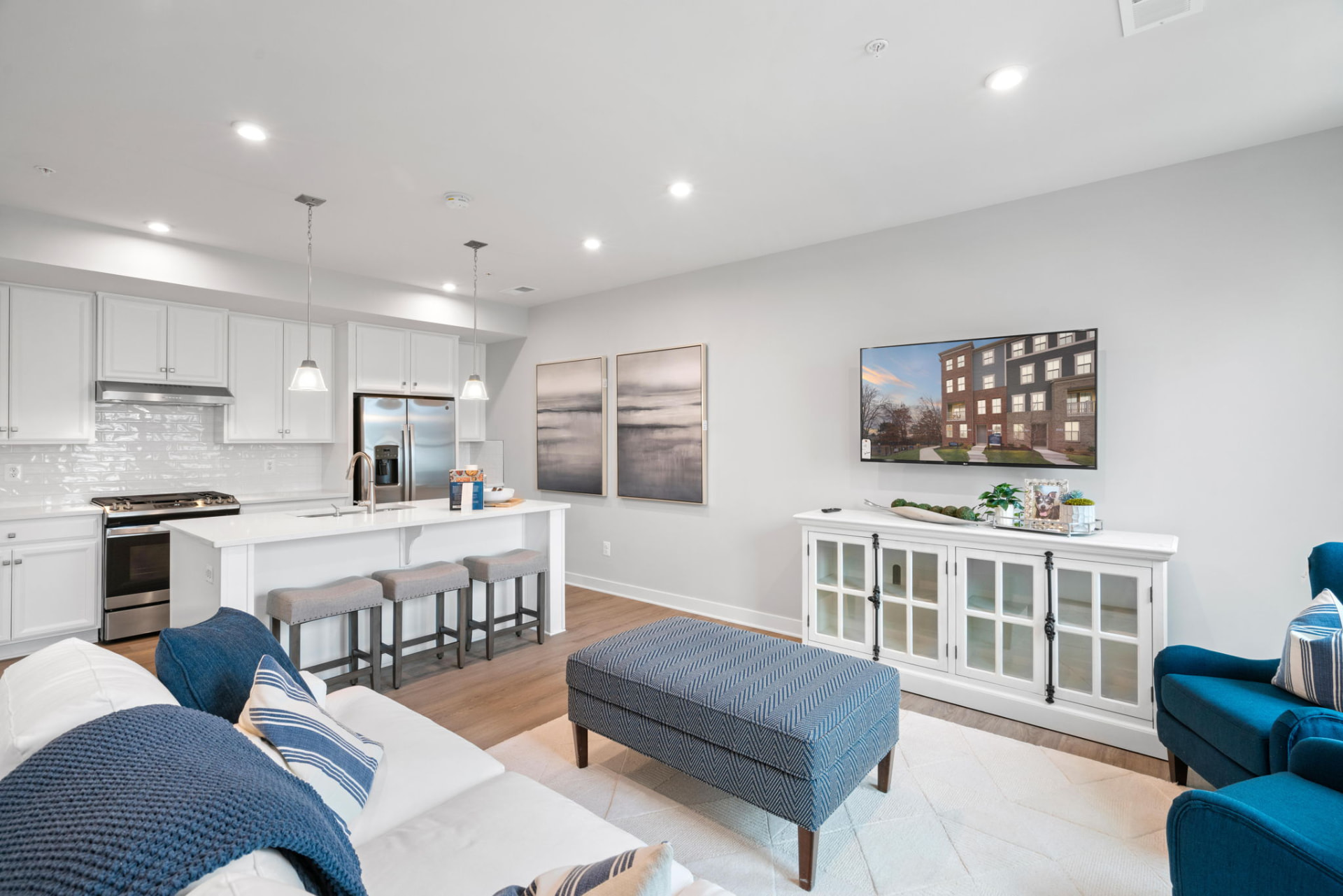 Bright residential living room open to a white kitchen with island seating